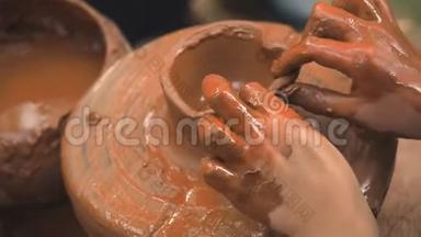 旋转陶工`的车轮和粘土器皿从上面。 一个小孩用陶工上的泥杯雕刻他`手
